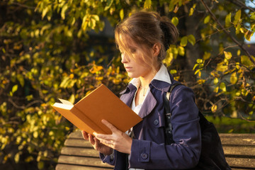 Ragazza sulla panchina in un parco che legge un libro