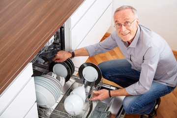 Senior man in kitchen, empty out the dishwasher 5