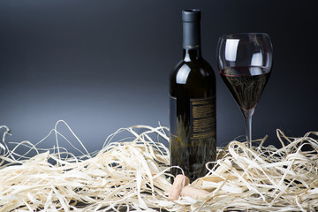 Red wine bottle and glass with cork in straw