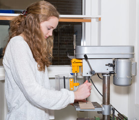 Teenage girl operating electric drilling machine