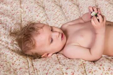 Cute blonde baby girl with beautiful blue eyes lying on bed