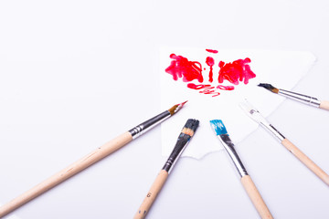 Red blob and paint brushes on a white background