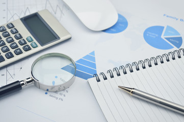 Book, magnifying glass, pen and calculator on financial chart an