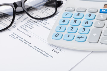 Black glasses and calculator over utility bill