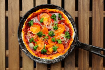 Raw round pizza with yellow cherry tomatoes, onion, garlic and b