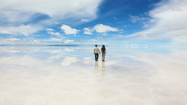Man and woman walking away on the lake Salar de Uyuni, Bolivia
