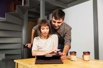 Young couple with tablet computer sitting at the table