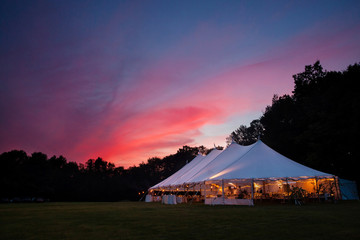 An event tent at night with a sunset during a wedding - obrazy, fototapety, plakaty