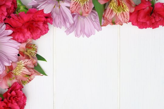 Corner border of pink flowers against white wood