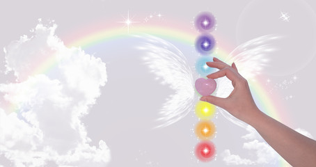 Hand holding Rose Quartz heart and The Seven Chakras