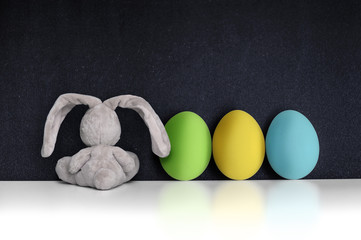 Easter Bunny with colored eggs on the black chalkboard - 80934097