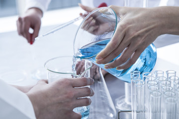 Researcher that pouring blue liquid
