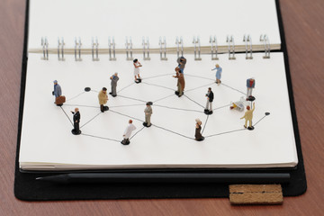 close up of miniature people with social network diagram on open