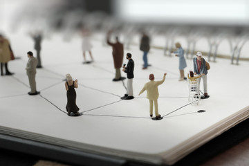 close up of miniature people with social network diagram on open