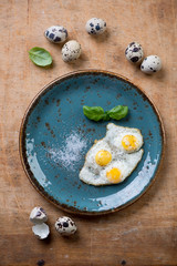 Turquoise plate with fried quail eggs, view from above