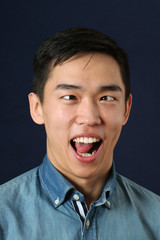 Funny young Asian man showing his tongue and making face