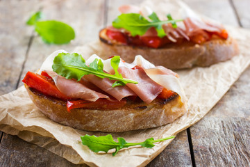 bruschetta with roasted peppers, prosciutto and arugula