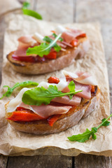 bruschetta with roasted peppers, prosciutto and arugula