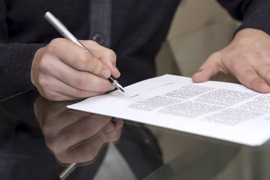 Hands of man signing formal paper