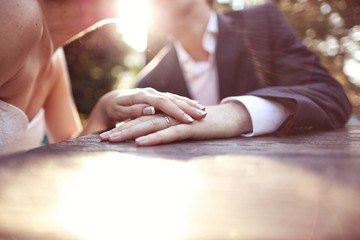 Holding hands with wedding ring in the sunlight