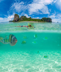 half above and underwater of a woman snorkeling in Thailand