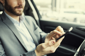 Man in car. Typing text message  on mobile phone