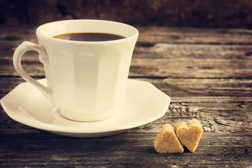 cup of coffe and brown cane sugar with shape of heart on old woo