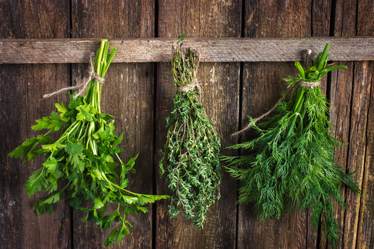 Bunch of thyme, dill and parsley hanging  on old wooden board