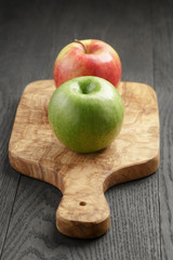 two ripe apples on olive cutting board