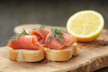 baguette slices with curred salmon and dill on wood table