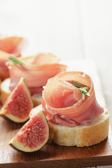 canapes with jamon and figs on wooden board