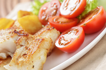 fried fish fillet with vegetables on wood table