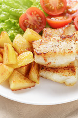 fried fish fillet with vegetables on wood table
