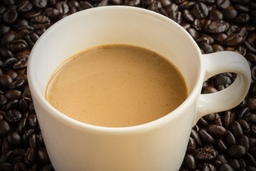 Hot latte coffee cup on coffee beans background.