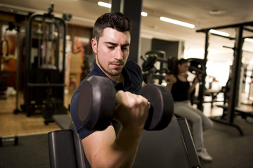 Young man training biceps at gym