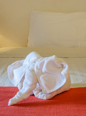White towel in form of elephant on bed