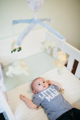 Little baby boy in his cot with his mobile toy in the foreground