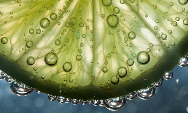 Slice of transparent lime in water with bubbles
