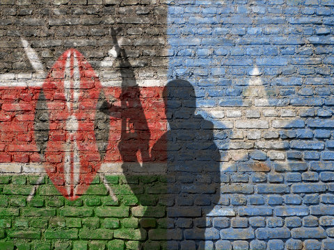 Shadow Of Man On Kenya And Somalian Flag Painted Brick Wall