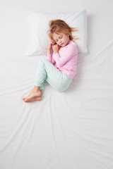 Top view of little girl sleeping in Foetus pose