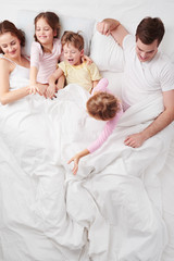 Family of five under blanket in the morning