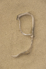 Fototapeta na wymiar Zahl 9 aus Treibholz auf Sand