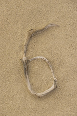 Fototapeta na wymiar Zahl 6 aus Treibholz auf Sand