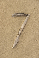 Zahl 7 aus Treibholz auf Sand