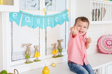 Cute toddler boy with easter decoration eating cookie