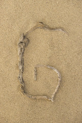 Fototapeta na wymiar Alphabet Buchstabe G aus Treibholz auf Sand