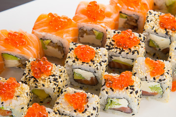Japanese tasty sushi set on a white plate over black background