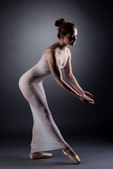 Fototapeta na wymiar Sexy ballerina dancing in studio, on gray backdrop