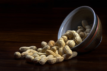 peanuts out of a ceramic bowl, dark background