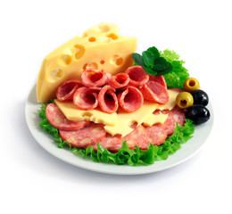 sliced sausage and cheese with herbs and olives on a white plate